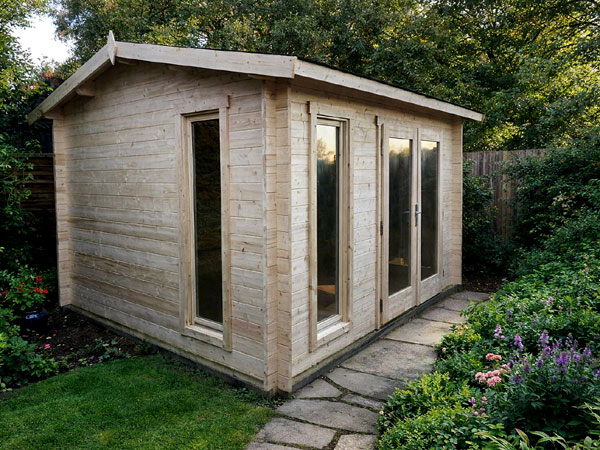 An apex log cabin with large windows and a sloping roof