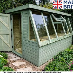 A green wooden greenhouse with open door in garden. Beautiful flowers and plants around it.