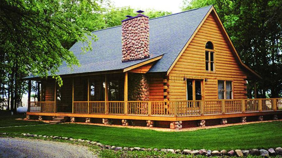 Home 41 A log cabin with a large porch and wooden deck surrounded by trees.