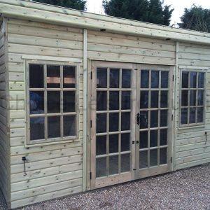 A wooden summerhouse with double doors and large windows, surrounded by trees and plants.