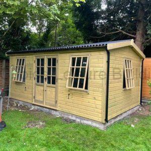 A wooden summerhouse with double doors and large windows, surrounded by trees and plants.